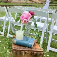 Crate with old book, candle, and flowers in vase